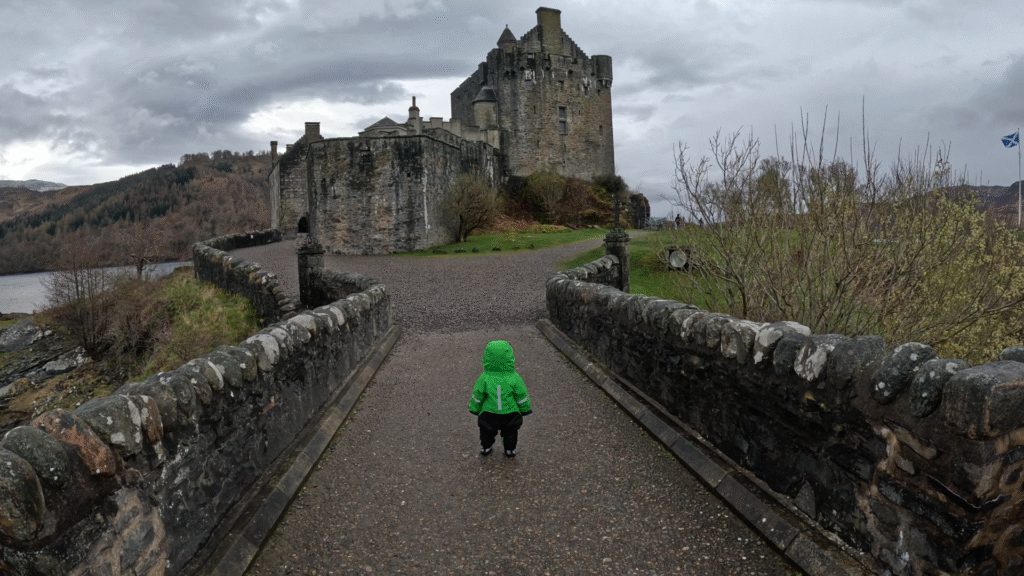 toddler standing in front of eilean donan castle, scottish highlands